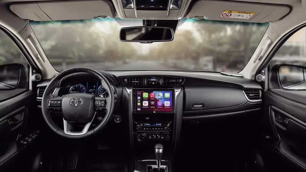 Interior da Toyota Hilux com painel, volante, central multimídia e câmbio automático