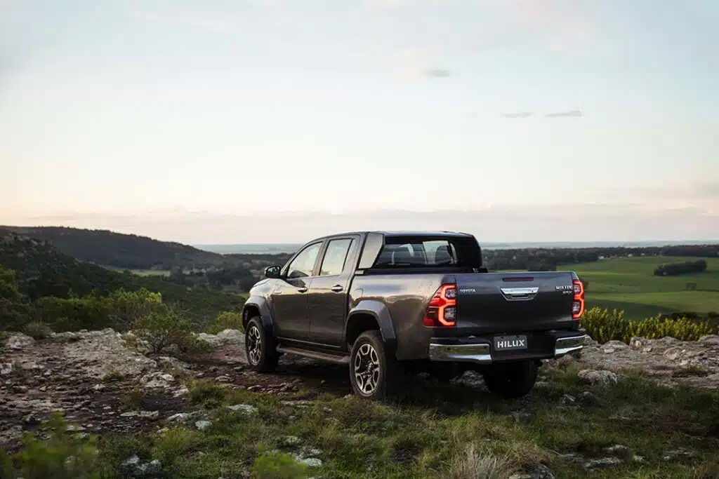 Toyota Hilux SRX Plus vista pela traseira em terreno rural; picape lidera mercado brasileiro